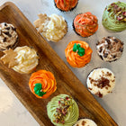 Assorted cupcakes with different flavors and decorations on a wooden tray.